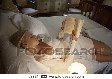 Stock Image - Girl reading in bed. Fotosearch