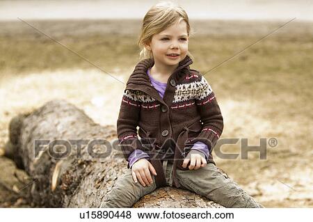 Girl sitting on log outdoors View Large Photo Image Stock Photo - Girl sitting on log outdoors. Fotosearch