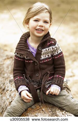 Girl sitting on log outdoors View Large Photo Image Stock Photo - Girl sitting on log outdoors. Fotosearch