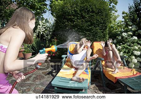Stock Photo - Girl sprays water on mum and sister. Fotosearch