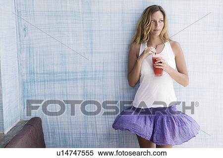 Girl standing up against blue wall with red smoothie in her hand View Large Photo Image Stock Photography - Girl standing up against blue wall with red smoothie in her hand. Fotosearch