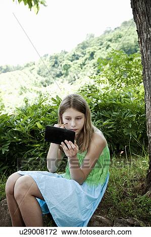 Girl under tree playing with make-up View Large Photo Image Stock Image - Girl under tree playing with make-up. Fotosearch