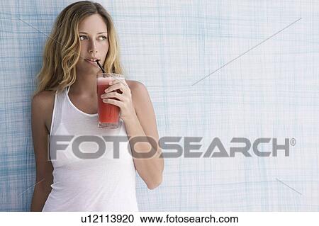 Girl up against blue wall with red smoothie, looking to the side View Large Photo Image Stock Image - Girl up against blue wall with red smoothie, looking to the side. Fotosearch