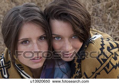 Stock Image - Girls covered in blanket looking up. Fotosearch