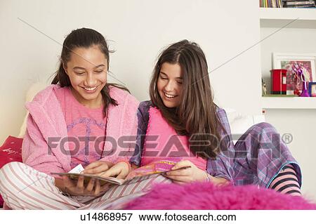 Stock Photo - girls reading magazine on bed. Fotosearch