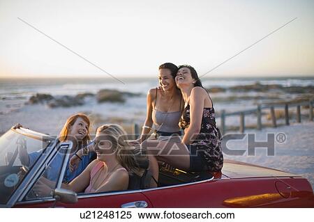 Stock Photography - Girls riding a red convertible car. Fotosearch