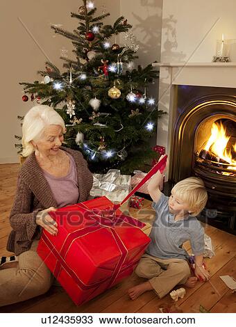 Grandson opens a present with his Granny View Large Photo Image Stock Image - Grandson opens a present with his Granny. Fotosearch