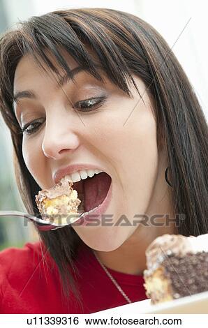 Stock Photograph - Greedy woman eating piece of cake. Fotosearch