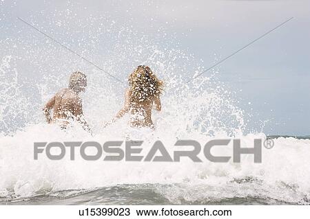 Guy and girl jumping into wave View Large Photo Image Stock Image - Guy and girl jumping into wave. Fotosearch