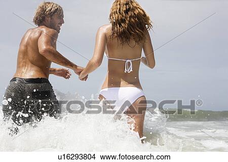 Guy and girl running into ocean View Large Photo Image Picture - Guy and girl running into ocean. Fotosearch