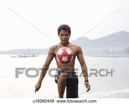Stock Photo - Guy playing football on beach. Fotosearch
