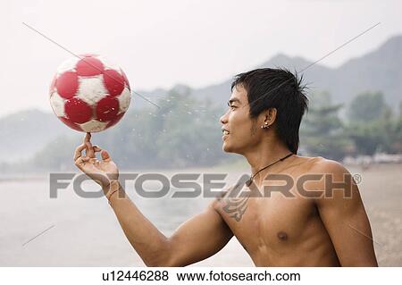 Guy spinning football on finger on beach View Large Photo Image Stock Photo - Guy spinning football on finger on beach. Fotosearch