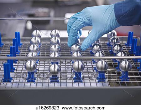 Stock Image - Hand touching engineered parts on rack. Fotosearch