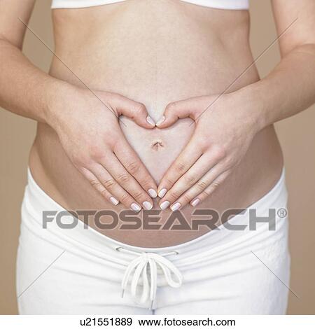 Stock Photo - Hands forming heart on pregnancy bump. Fotosearch