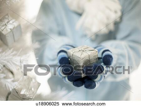 Hands holding present by Xmas tree View Large Photo Image Stock Photography - Hands holding present by Xmas tree. Fotosearch