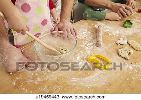 Stock Image - Hands of family cooking together. Fotosearch