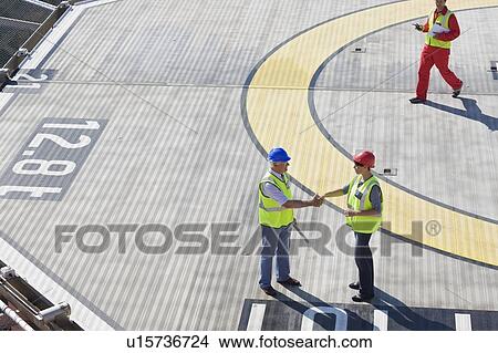 Picture - Handshaking workers on helistop. Fotosearch