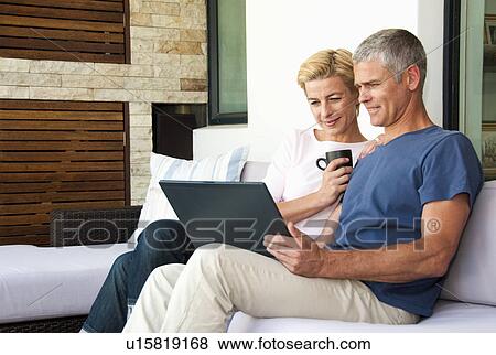 Stock Photo - Happy couple look at lap top. Fotosearch