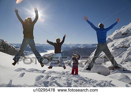 Stock Photo - Happy family jumps in winter mountains. Fotosearch