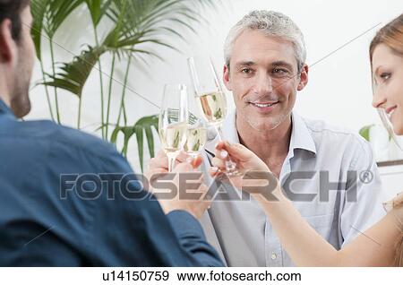 Stock Photo - Happy smiling friends toast wine glasses. Fotosearch