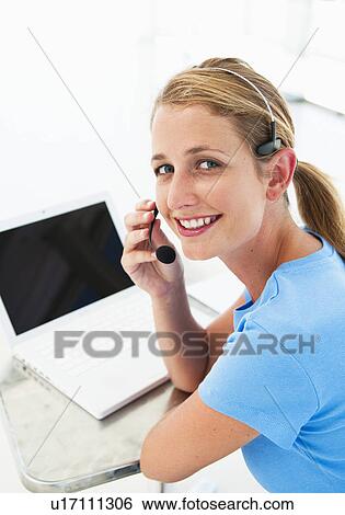 Stock Photograph - Happy woman in office with headset. Fotosearch