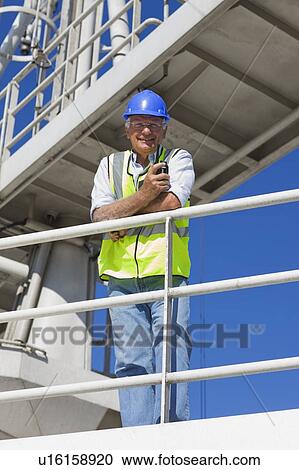 Stock Image - Harbour worker standing on guardrail. Fotosearch
