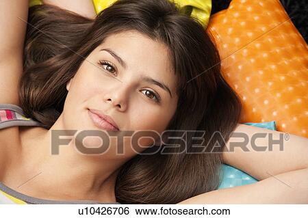 Stock Photograph - Headshot of a woman lying on cushions. Fotosearch