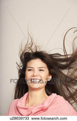 Stock Image - Headshot of a young woman hair flying. Fotosearch