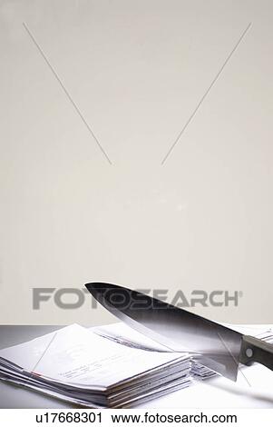 Stock Image - Knife cutting through bills. Fotosearch