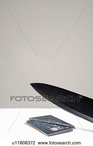 Stock Image - Knife cutting through credit cards. Fotosearch