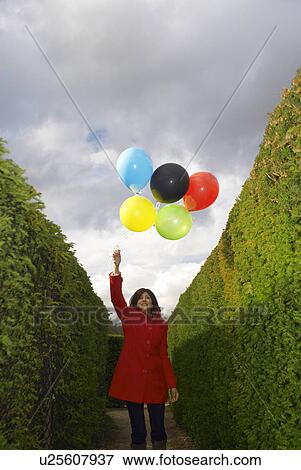 Lady holding balloons in a maze View Large Photo Image Stock Photo - Lady holding balloons in a maze. Fotosearch
