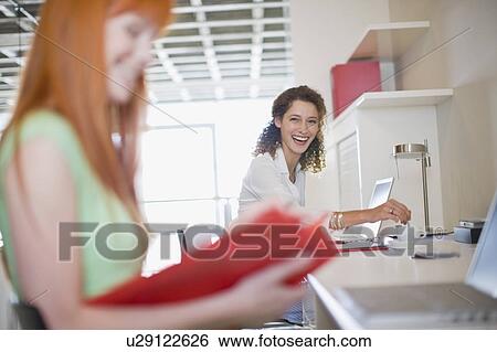 Laughing businesswomen working at desks View Large Photo Image Stock Photograph - Laughing businesswomen working at desks. Fotosearch