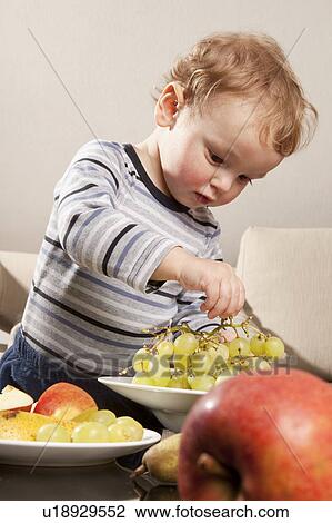 Stock Image - Little boy eating fruit. Fotosearch