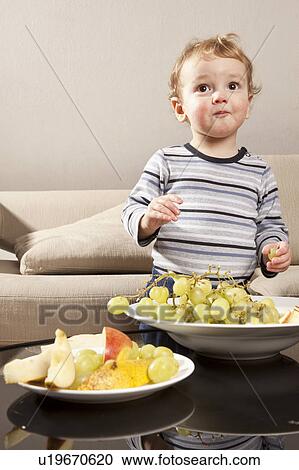 Stock Image - Little boy eating grapes. Fotosearch