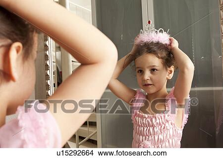 Picture - Little girl putting crown on her head. Fotosearch