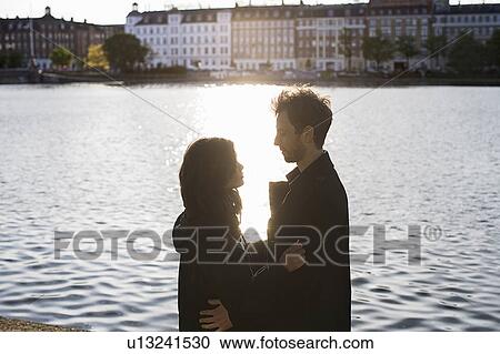 Lovers stand by a lake in a city View Large Photo Image Stock Image - Lovers stand by a lake in a city. Fotosearch