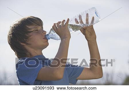 Stock Image - Low angle of boy drinking water. Fotosearch