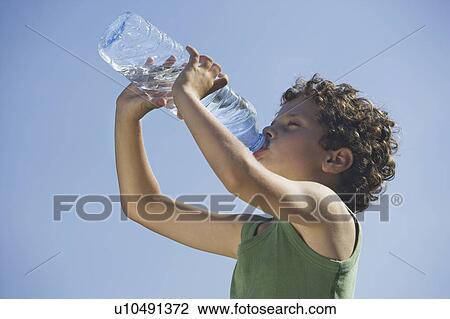 Stock Image - Low angle of young boy drinking water. Fotosearch