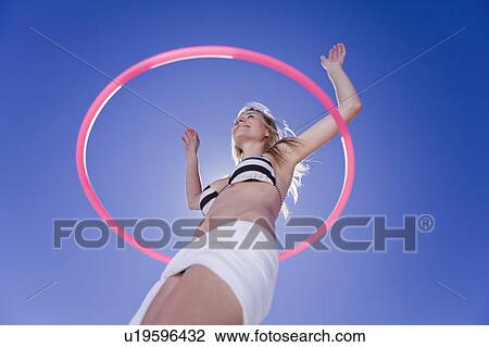 Low angle view of woman hula hooping View Large Photo Image Stock Image - Low angle view of woman hula hooping. Fotosearch