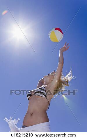 Stock Image - Low angle view of woman with beach ball. Fotosearch