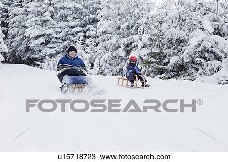 Man and boy sledding downhill View Large Photo Image Stock Image - Man and boy sledding downhill. Fotosearch