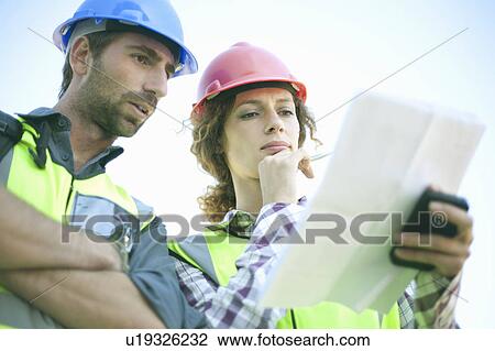 Man and woman in hard hats, with plans View Large Photo Image Stock Image - Man and woman in hard hats, with plans. Fotosearch