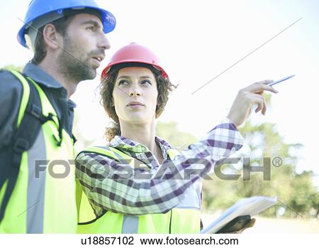 Man and woman, talking in hard hats View Large Photo Image Stock Image - Man and woman, talking in hard hats. Fotosearch