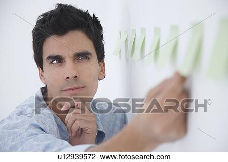 Stock Image - Man arranging post-it notes and thinking. Fotosearch