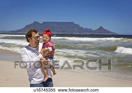 Man carrying baby girl on beach View Large Photo Image Stock Photography - Man carrying baby girl on beach. Fotosearch