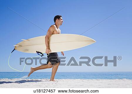 Man carrying surfboard on beach View Large Photo Image Stock Photo - Man carrying surfboard on beach. Fotosearch