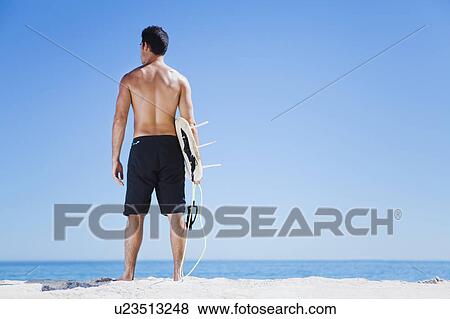Man carrying surfboard on beach View Large Photo Image Stock Photo - Man carrying surfboard on beach. Fotosearch