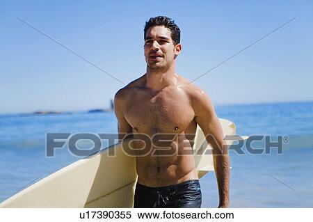 Man carrying surfboard on beach View Large Photo Image Stock Photography - Man carrying surfboard on beach. Fotosearch