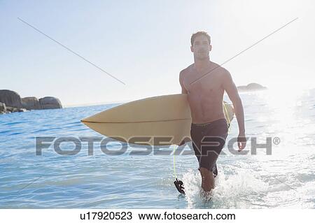 Man carrying surfboard out of water View Large Photo Image Stock Image - Man carrying surfboard out of water. Fotosearch