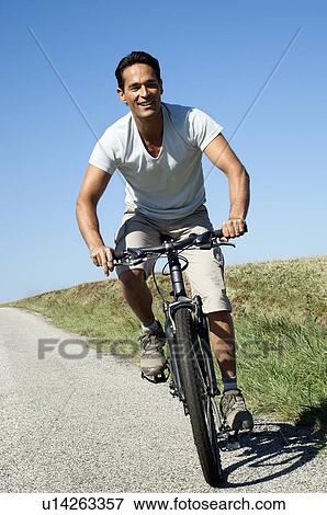 Man cycling on a country road View Large Photo Image Stock Photo - Man cycling on a country road. Fotosearch